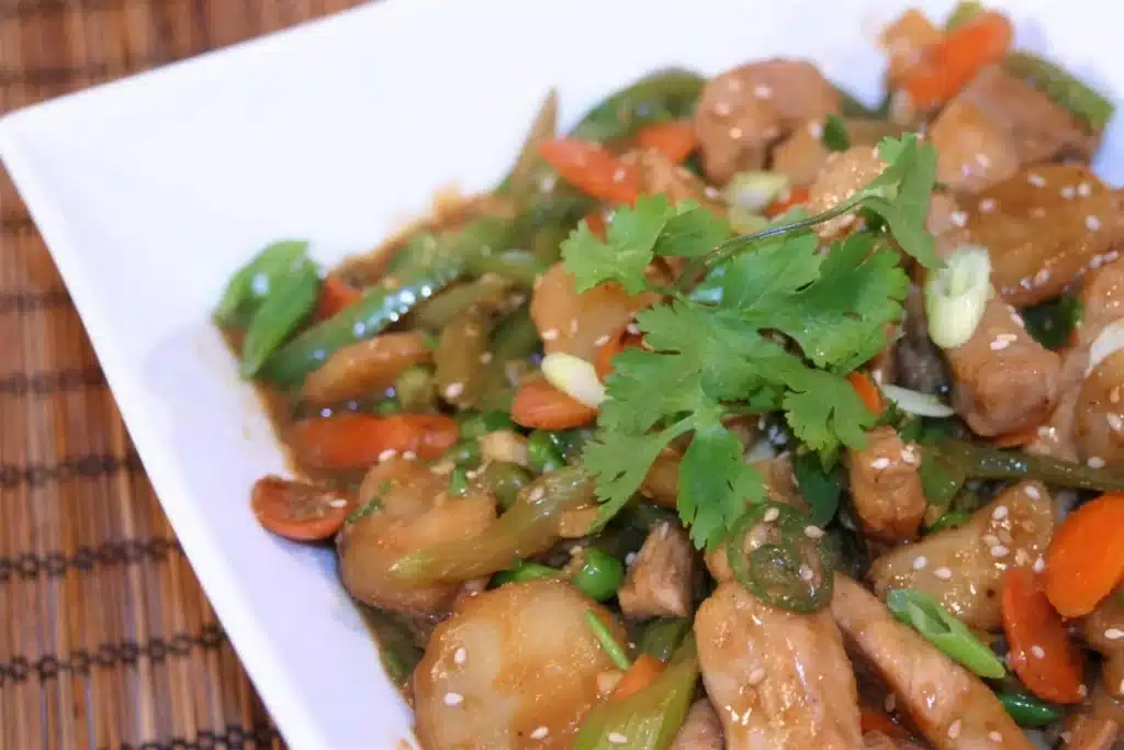 Spicy pork stir fry served over rice with cilantro and sesame seeds