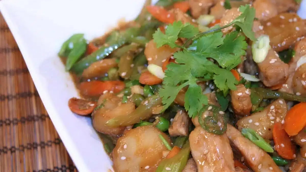 Spicy pork stir fry with carrots, celery and water chestnuts on a white plate