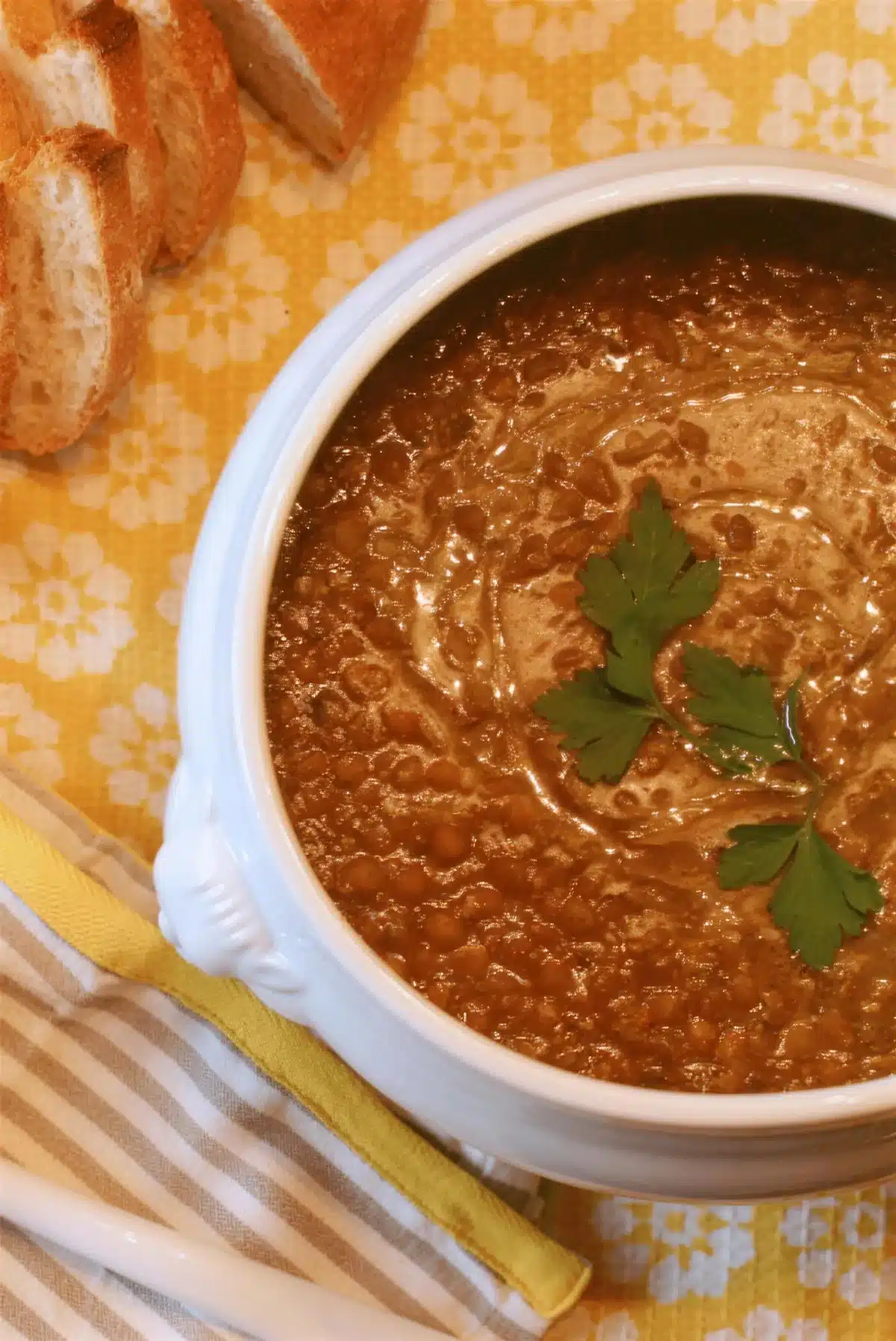 Curry lentil soup in a white tureen with crusty bread alongside