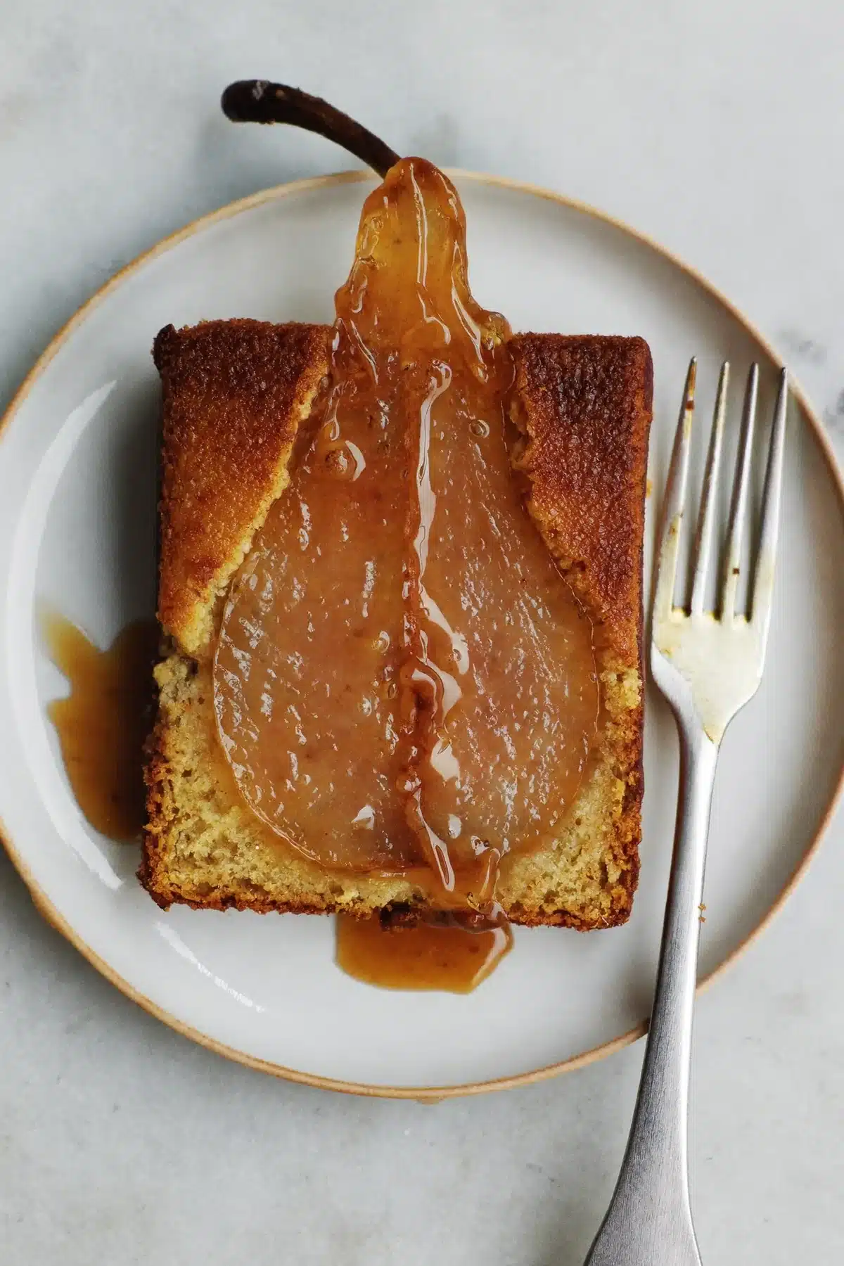 Pear upside down cake served as a slice with caramel pooling on the plate