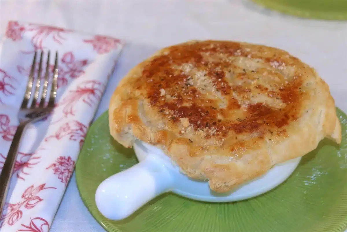 Individual pastry topped bake on a green plate beside a fork and a floral napkin