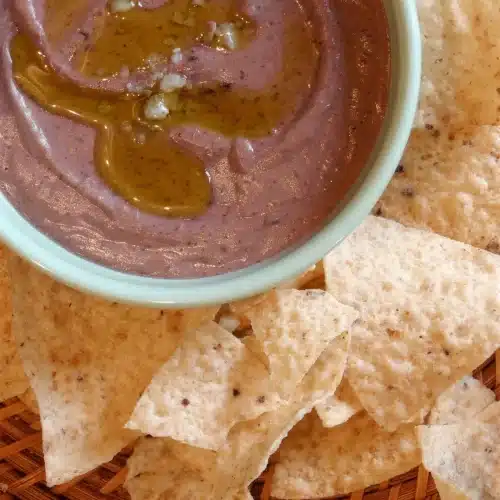 Overhead pale bowl of smooth spread ringed with tortilla chips