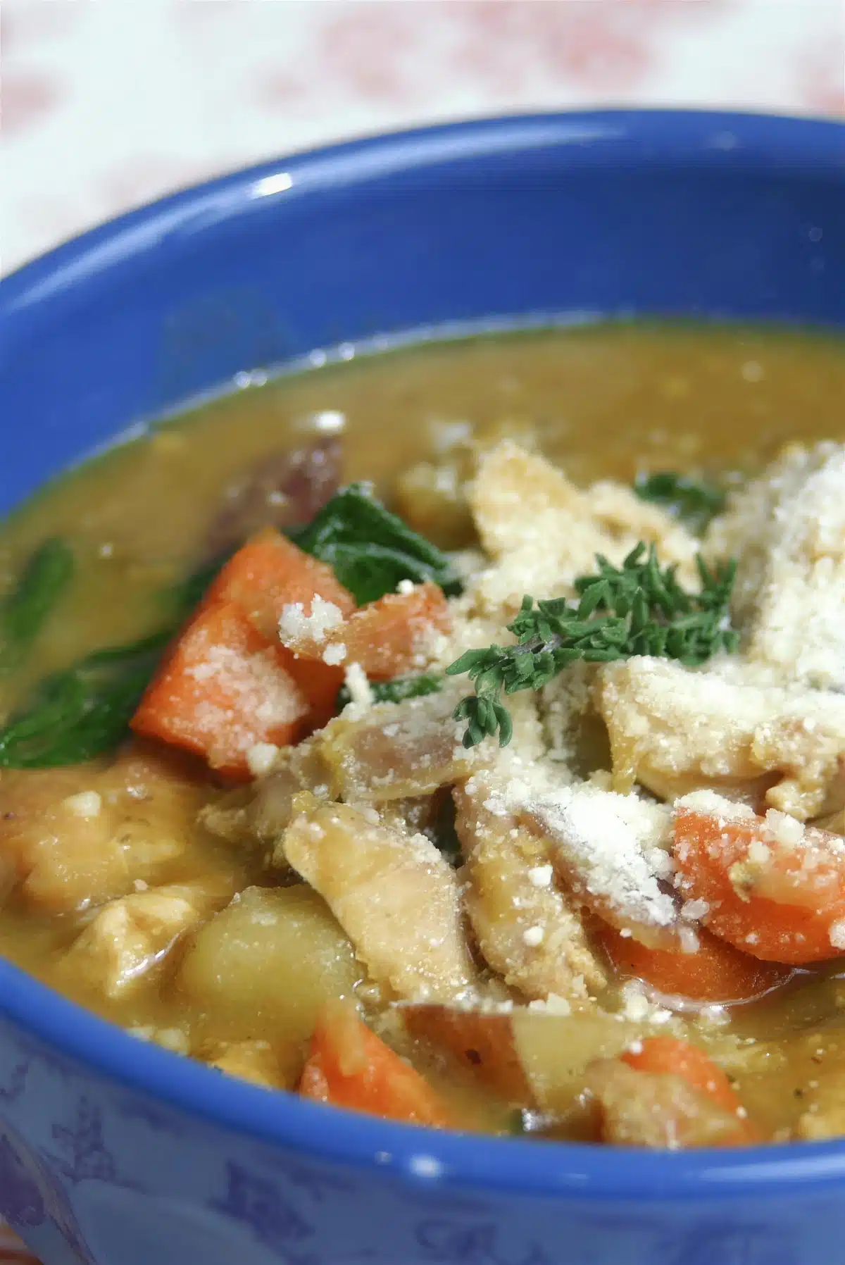 Chicken lentil stew in a blue bowl with parmesan and thyme