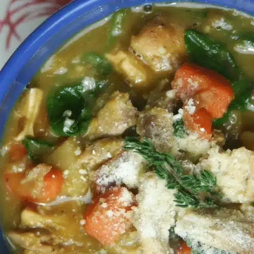 Overhead view of a blue bowl with carrots, greens and shaved cheese