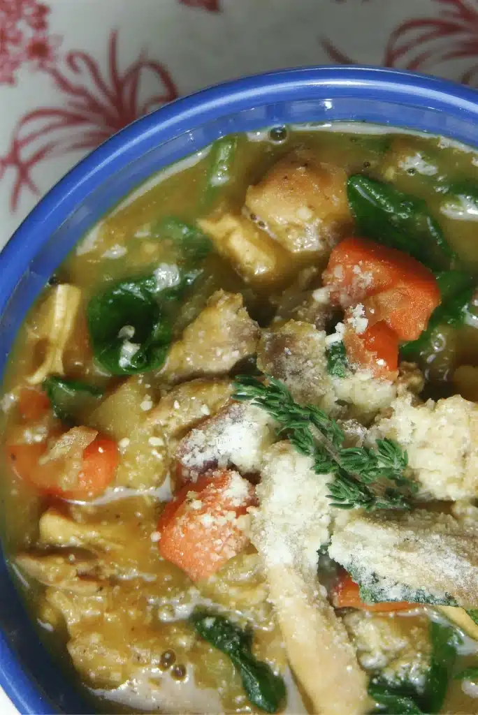 Overhead view of a blue bowl with carrots, greens and shaved cheese