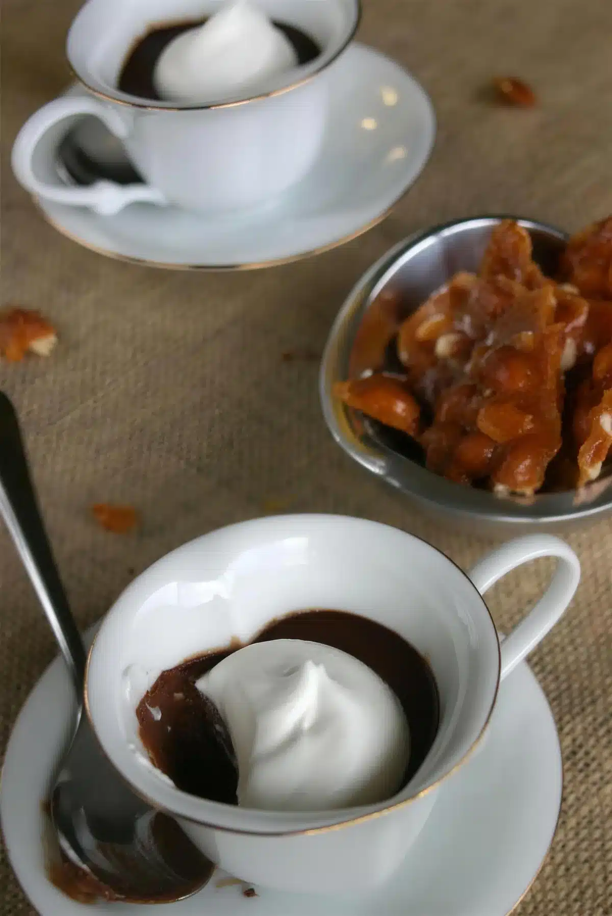 Chocolate pots de creme in a teacup with peanut brittle alongside