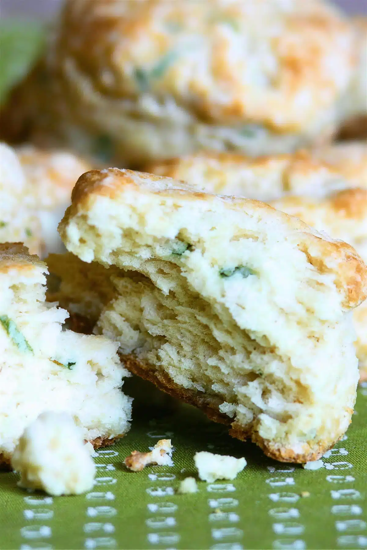A flaky biscuit torn open to show its separated layers and green flecks