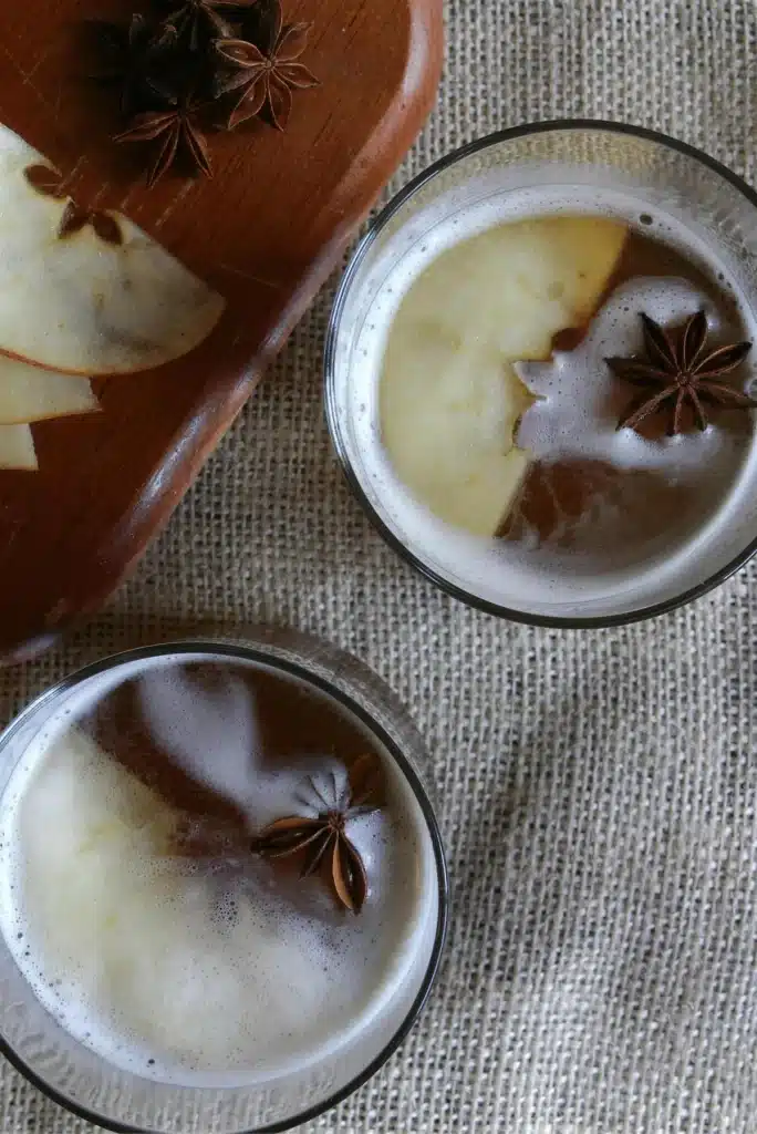 Two short glasses seen from above with star anise floating on the foam