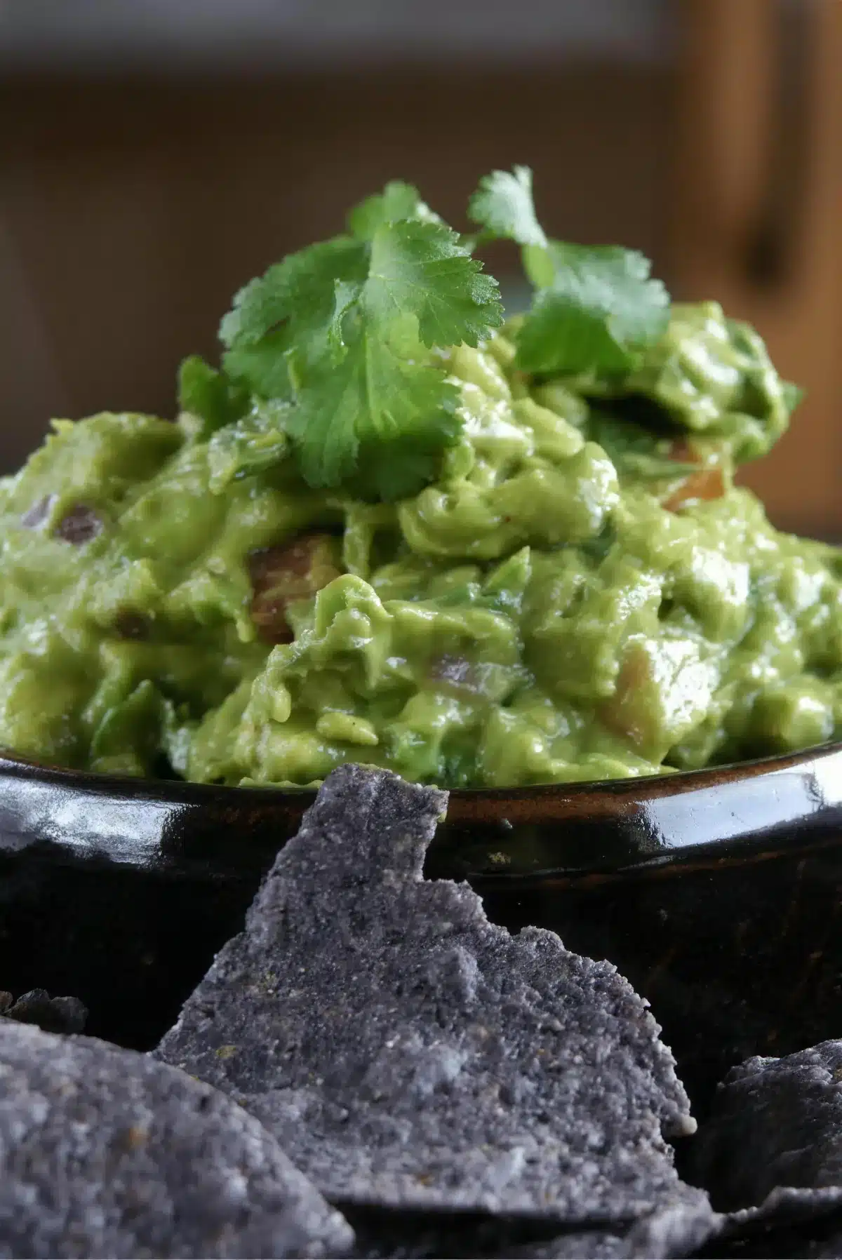 Spicy guacamole heaped in a black bowl and topped with cilantro
