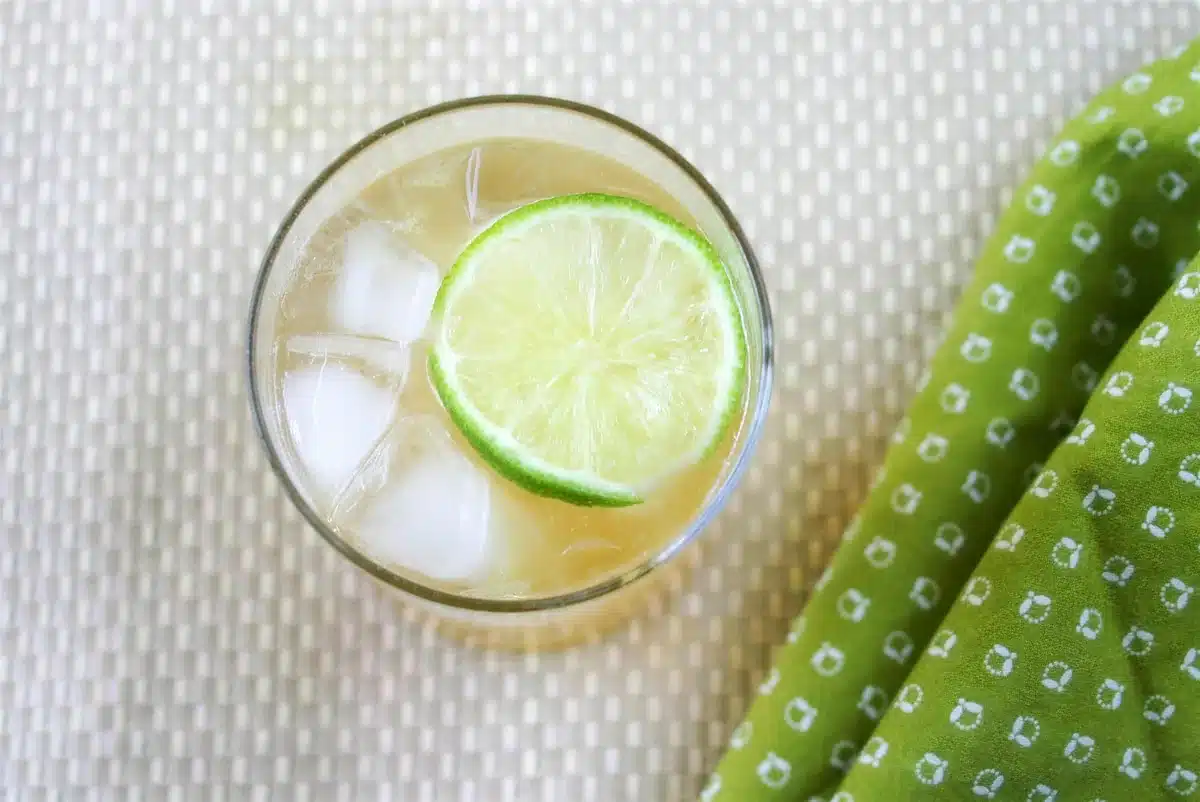 Overhead view of an iced drink with a lime wheel beside a folded green cloth