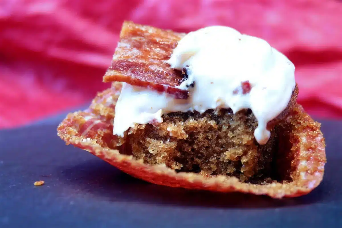 A maple bacon cupcake split open to show its tight amber crumb