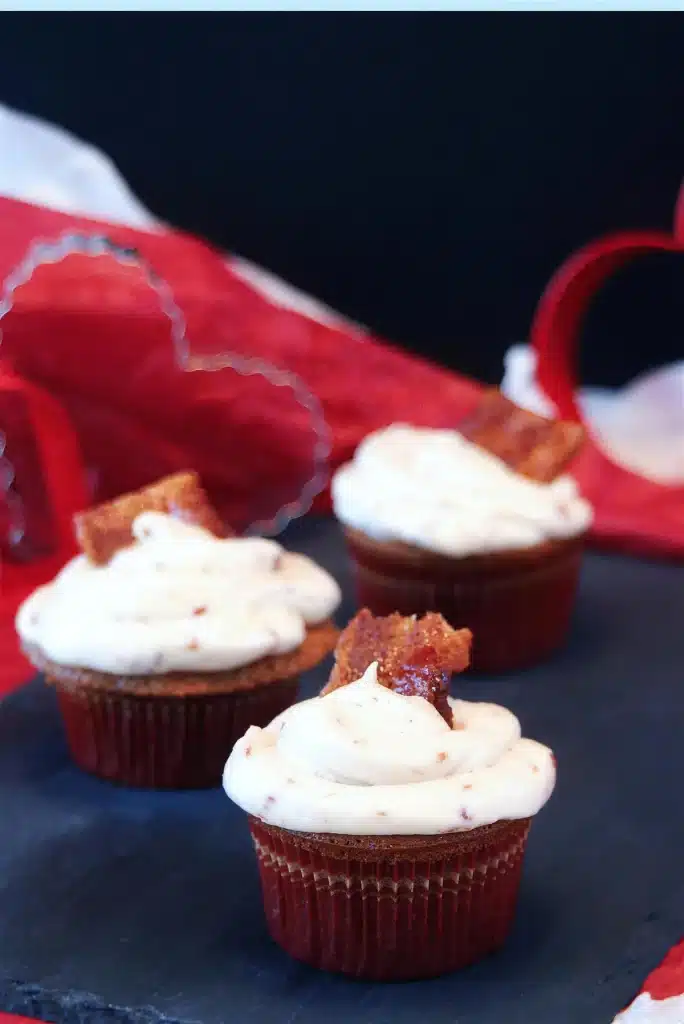 A single frosted cake in a red pleated liner against a scarlet cloth