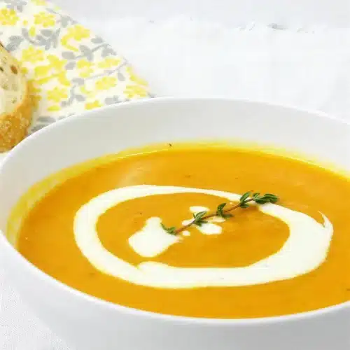 Overhead bowl of carrot parsnip soup with a swirl of lemon ginger cream and fresh thyme