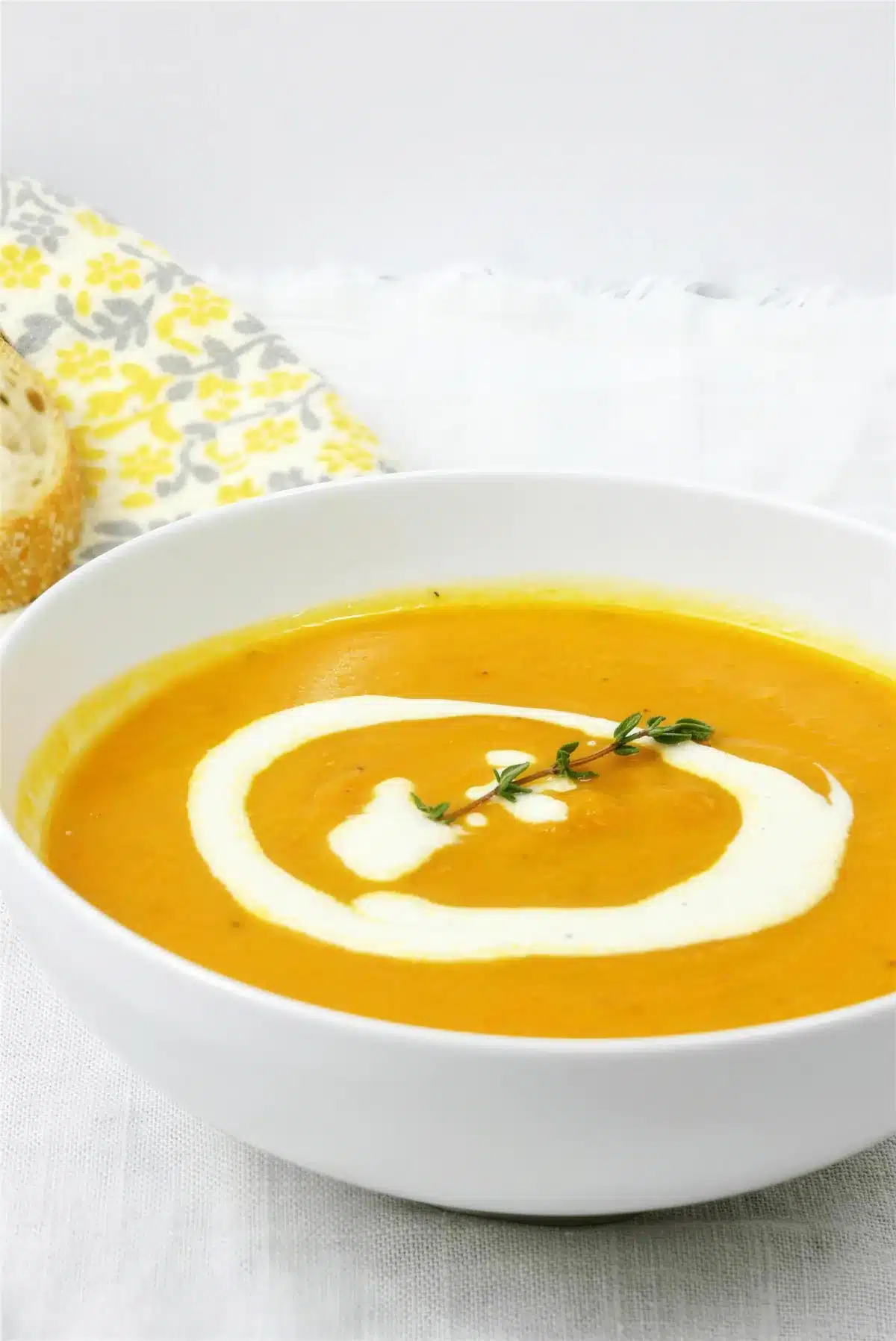Overhead bowl of carrot parsnip soup with a swirl of lemon ginger cream and fresh thyme