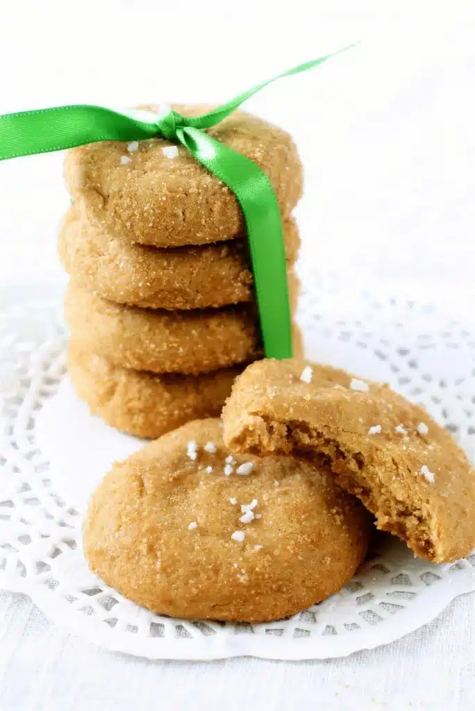 Butterscotch cookies stacked on a doily with one broken open to show the chewy middle