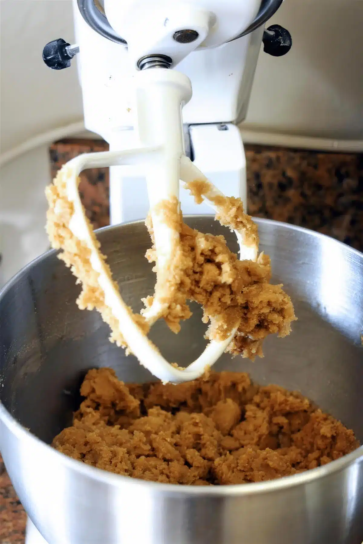 Thick dough clinging to the paddle of a stand mixer