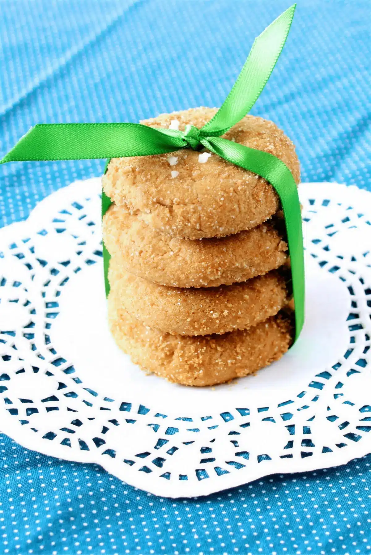 Butterscotch cookies stacked with a green ribbon on a blue polka dot cloth