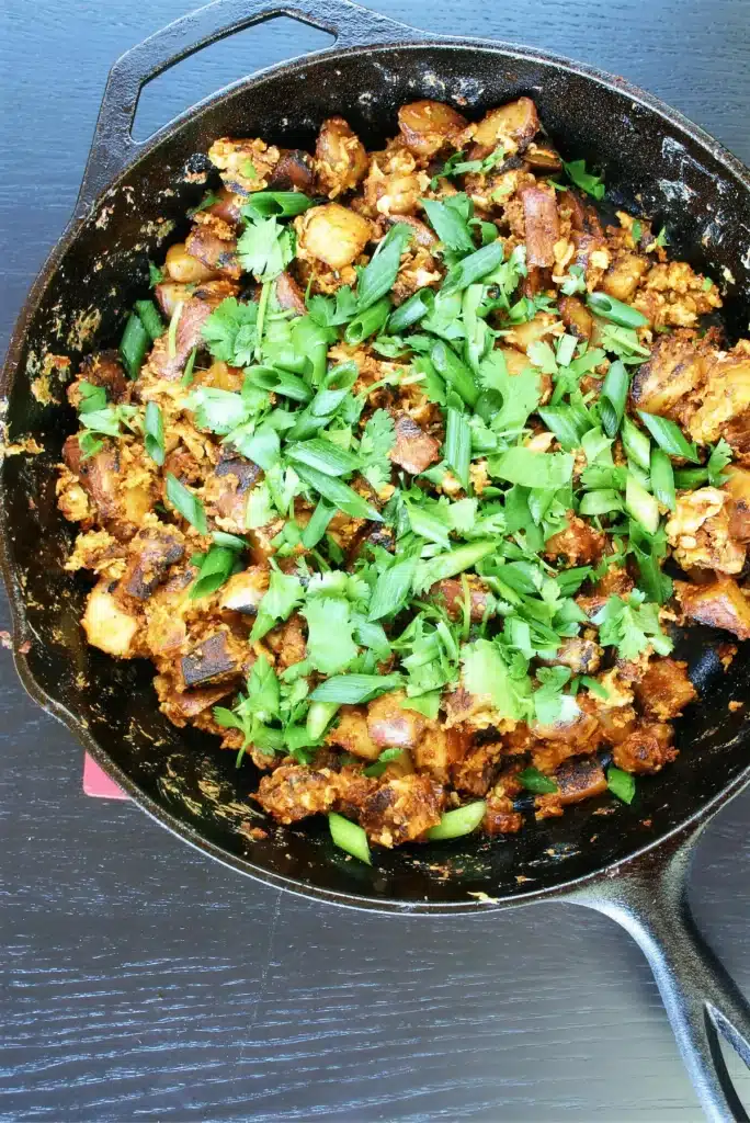 Chorizo hash in a cast iron skillet under scallions and cilantro
