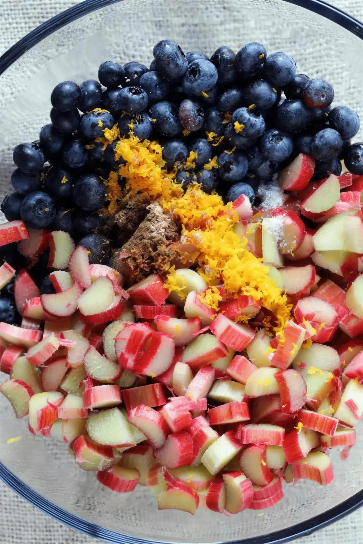 Berries and chopped pink stalks with orange zest in a glass bowl