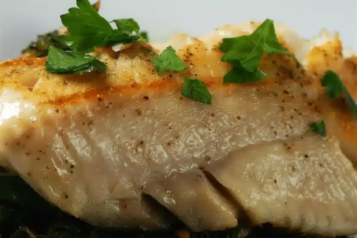 Pan seared cod fillet with a golden crust resting on garlicky chard