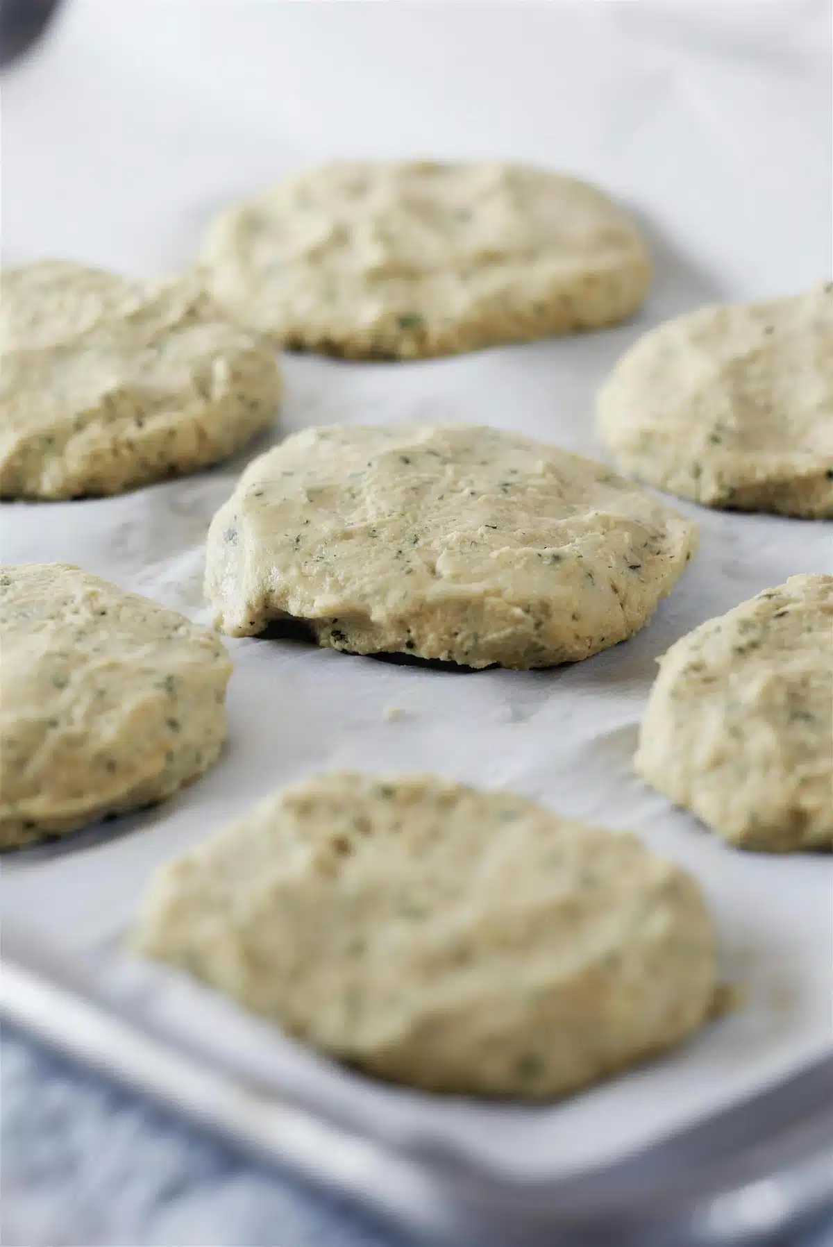 Shaped rounds of pale mixture resting on a parchment-lined tray