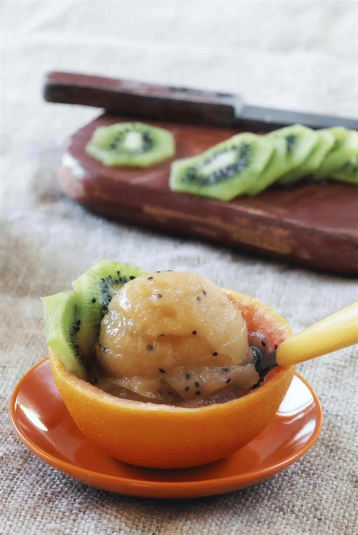 Kiwi sorbet in a hollowed grapefruit half beside sliced green fruit on a board