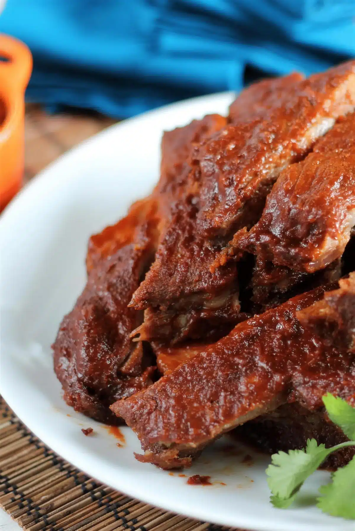 BBQ spare ribs piled on a white platter under a dark sticky glaze