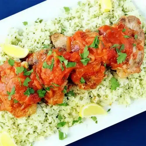 Braised chicken thighs under tomato sauce on herbed couscous with parsley