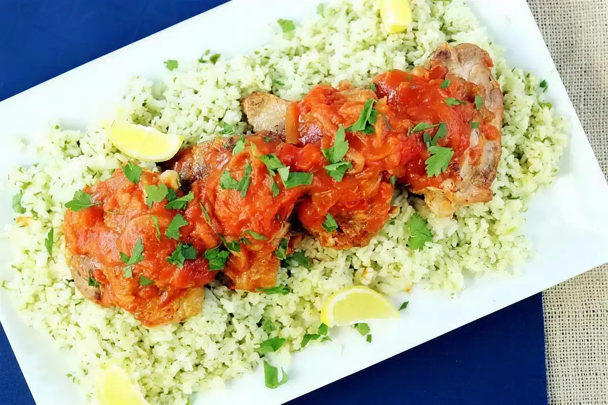Braised chicken thighs under tomato sauce on herbed couscous with parsley