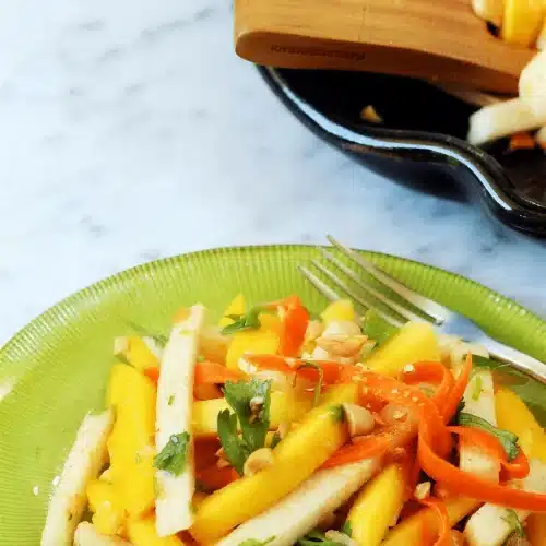 Jicama salad with mango and carrot on a green plate