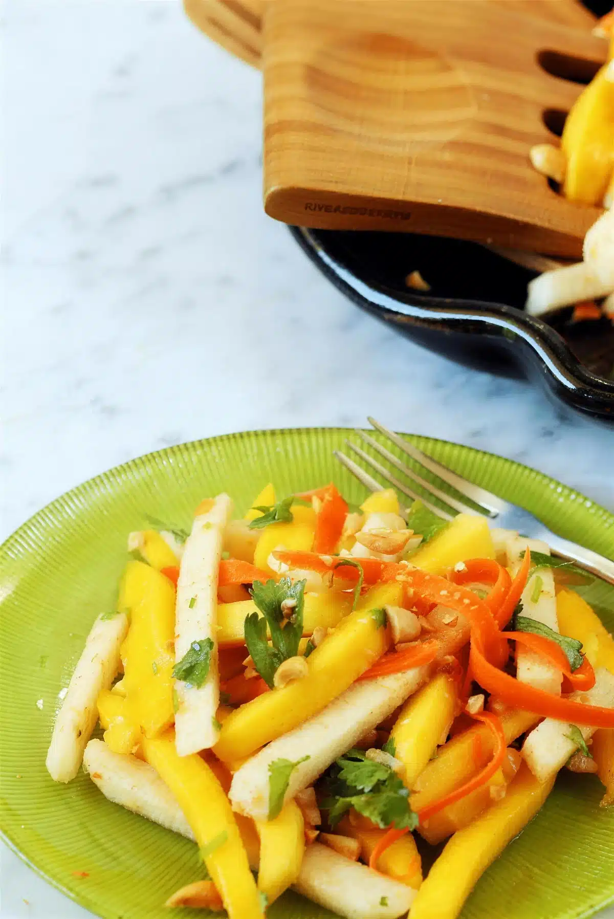 Jicama salad with mango and carrot on a green plate