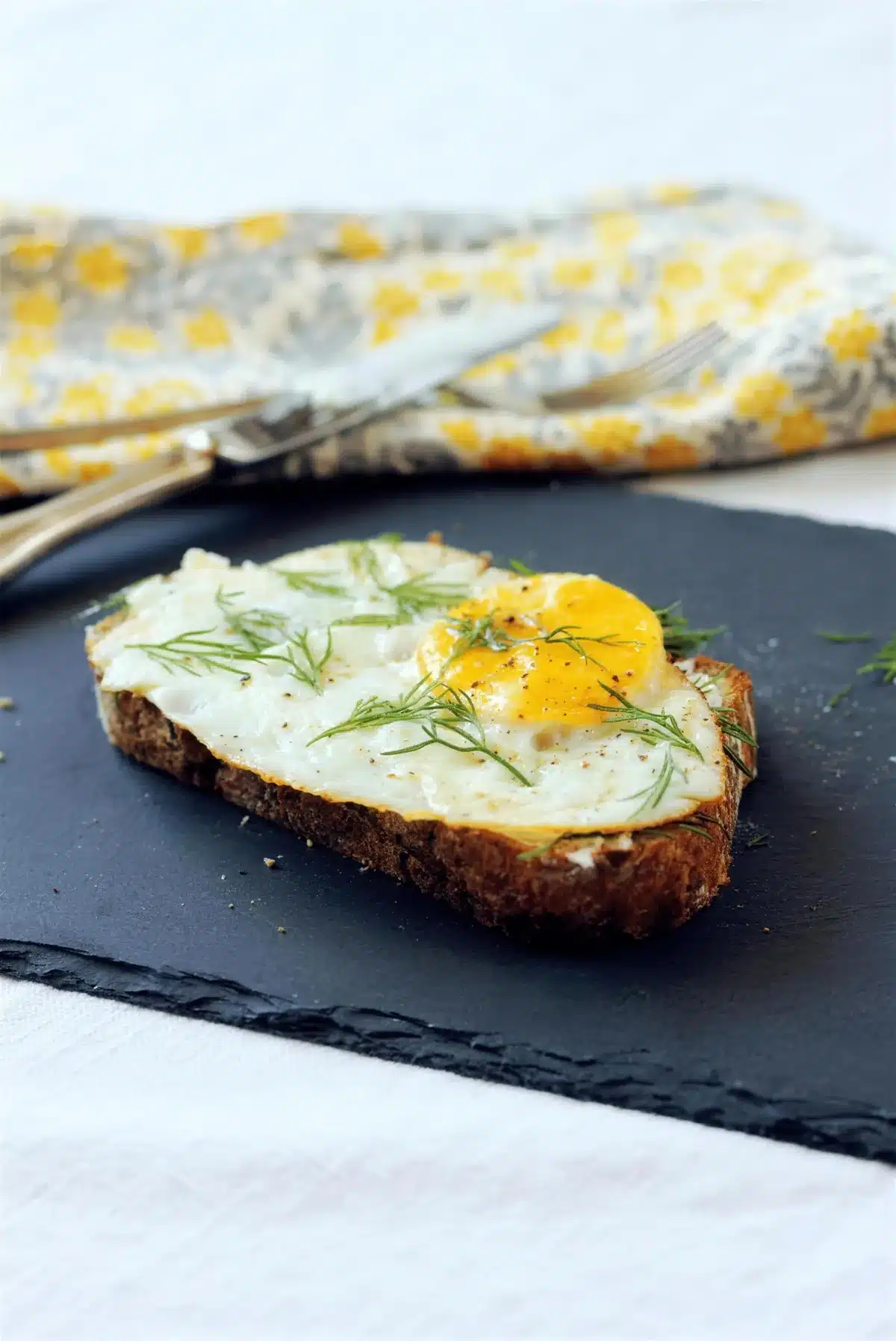 Open faced egg sandwich beside a folded gray and yellow napkin