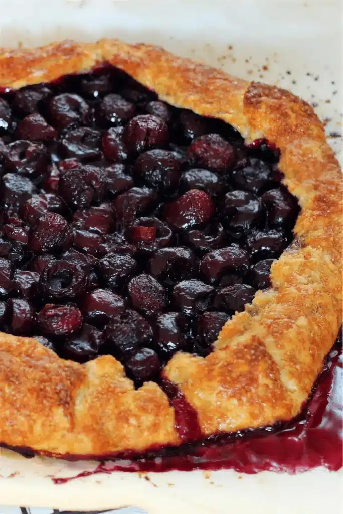 A round free-form tart on a pale plate with its edge crimped in loose folds