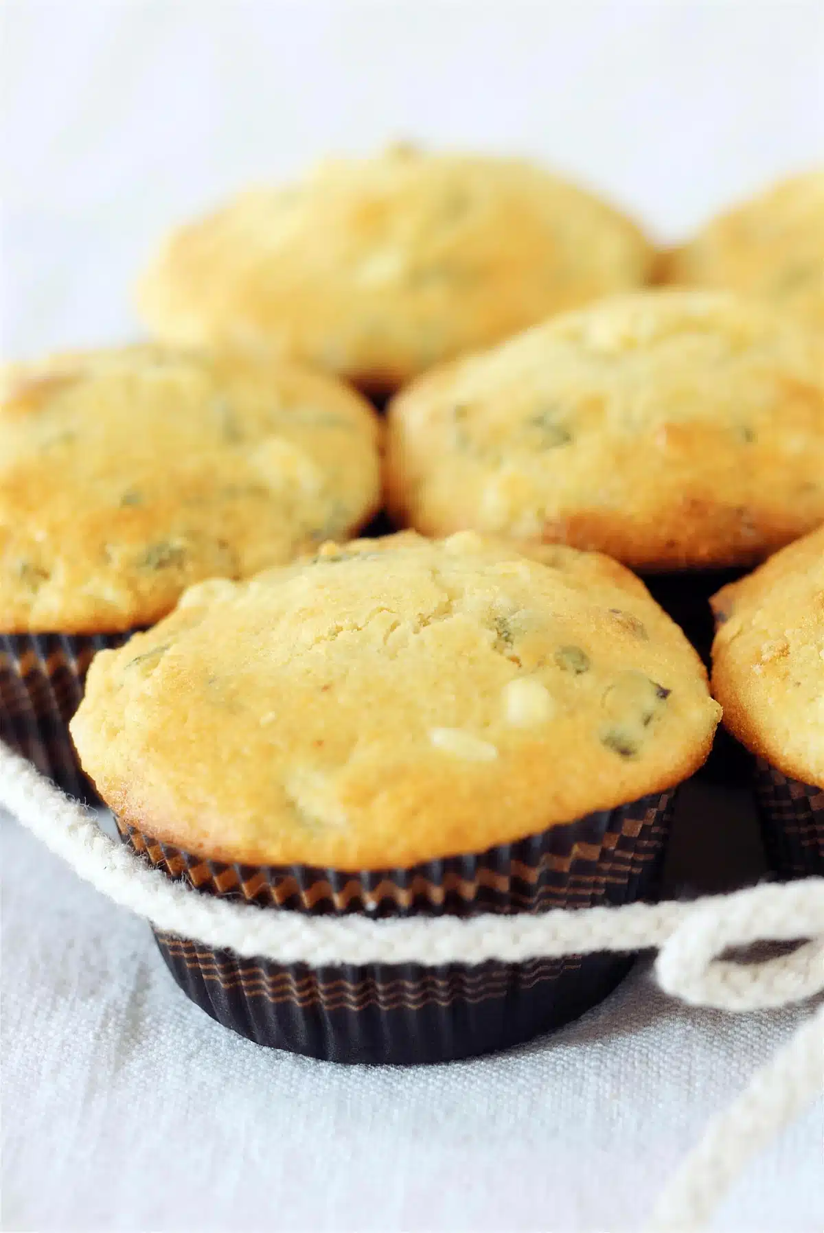 Cornbread muffins stacked in dark paper liners on a folded white cloth