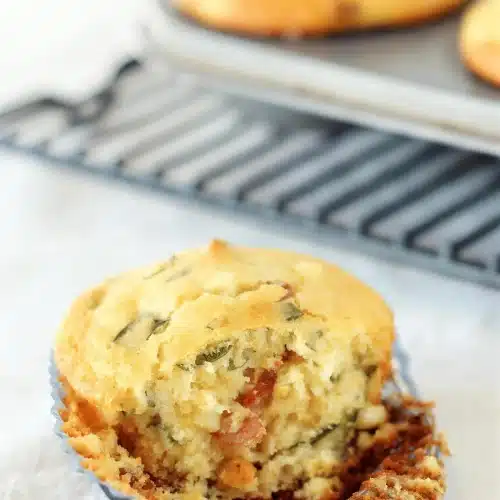 Cornbread muffins split open on a rack to show the bacon and basil in the crumb