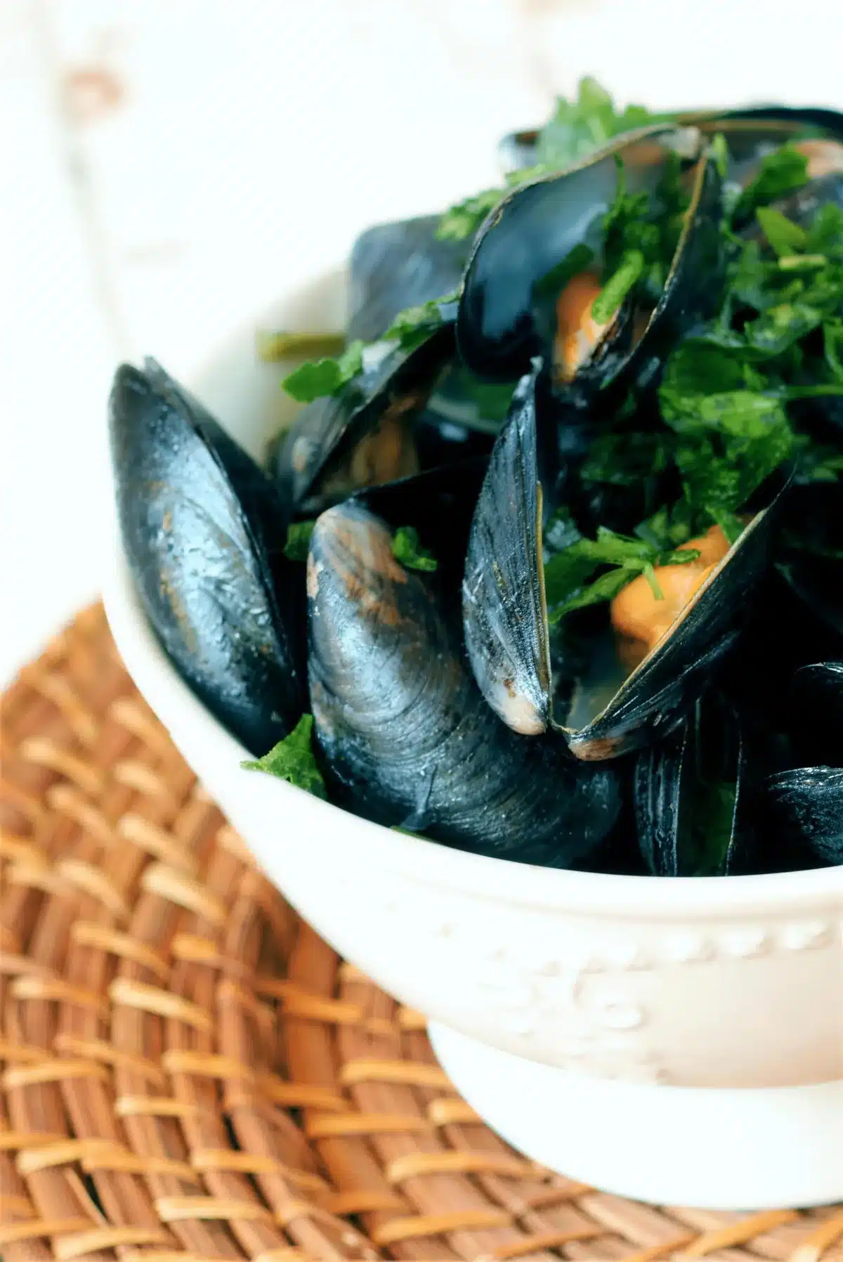 Close up of glossy open shells in a herb flecked broth