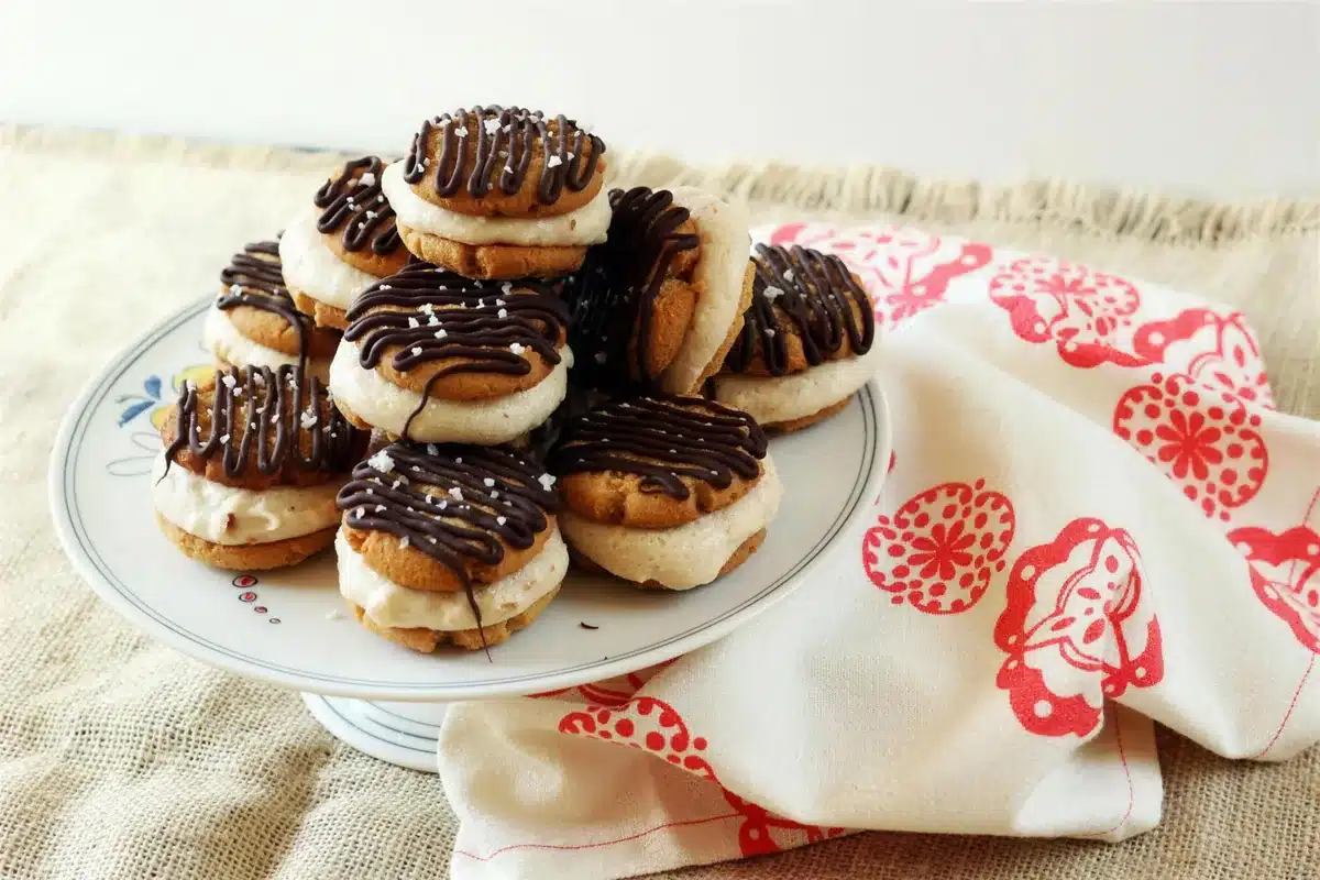 Ice cream sandwiches piled on a plate beside a red patterned cloth