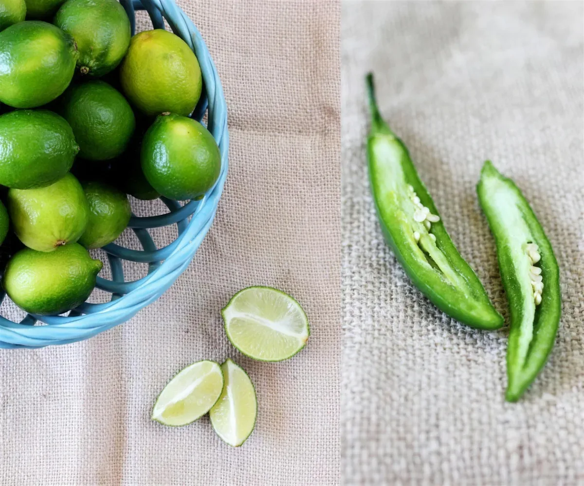 Limes in a blue basket beside halved serrano chiles