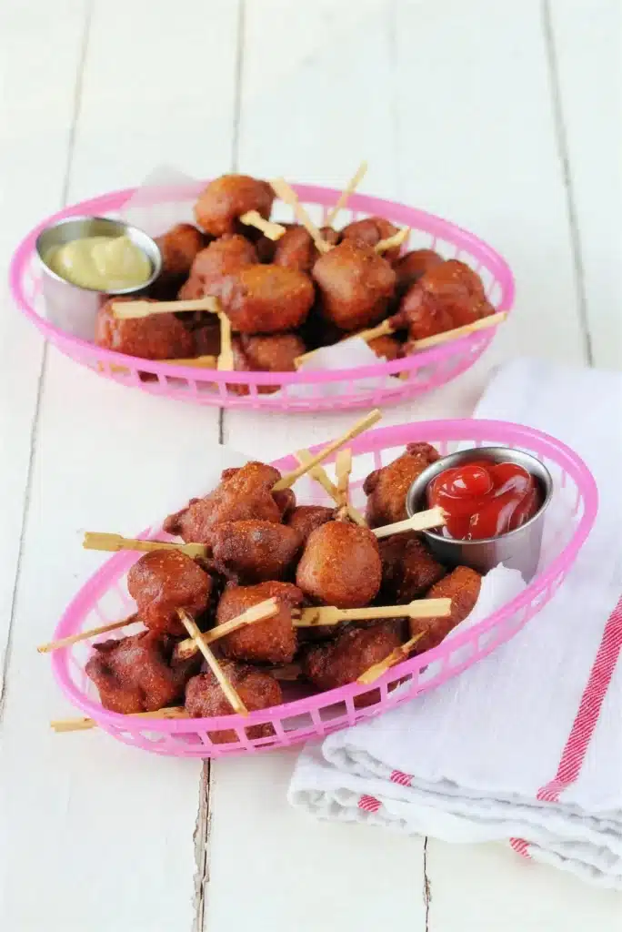 Two pink baskets of battered sausage bites on a white table