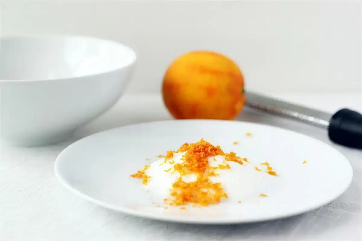 Citrus zest rubbed into granulated sugar on a white plate