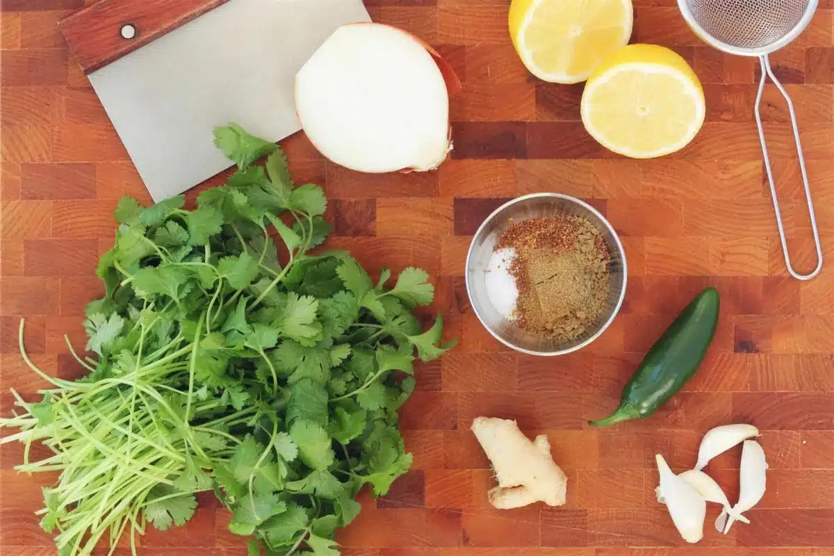 Aromatics for indian chicken wings laid out on a wooden board with a cleaver