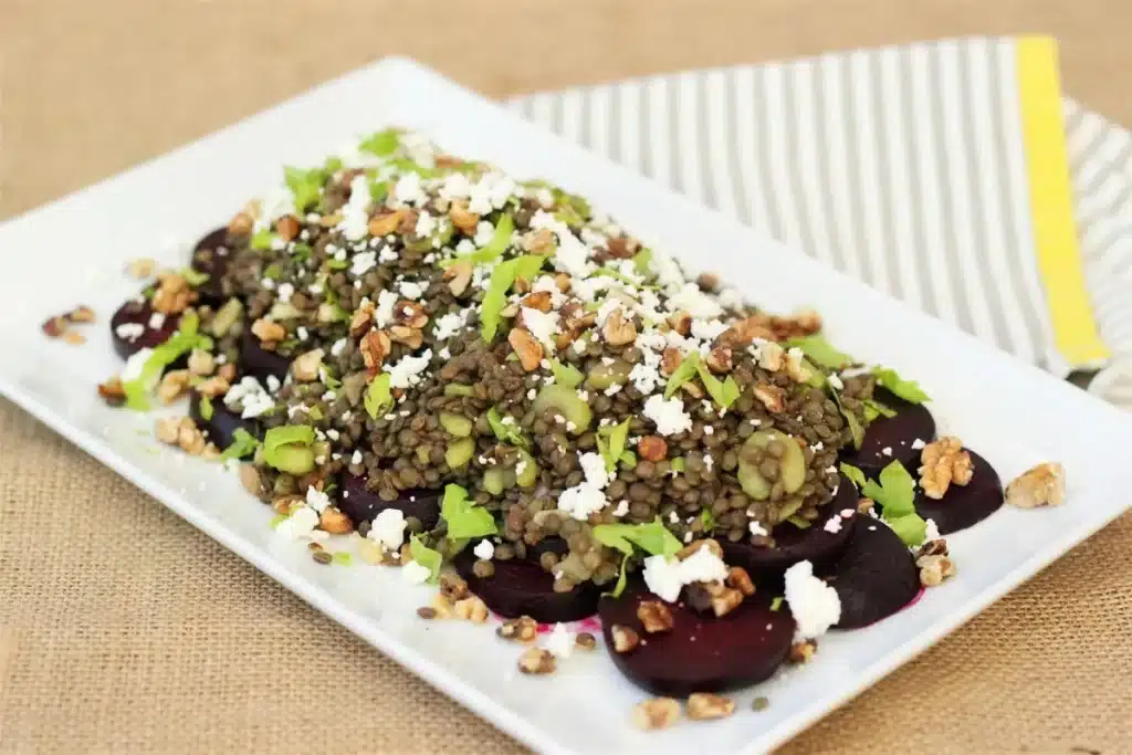 White rectangular platter of dressed pulses over sliced roots