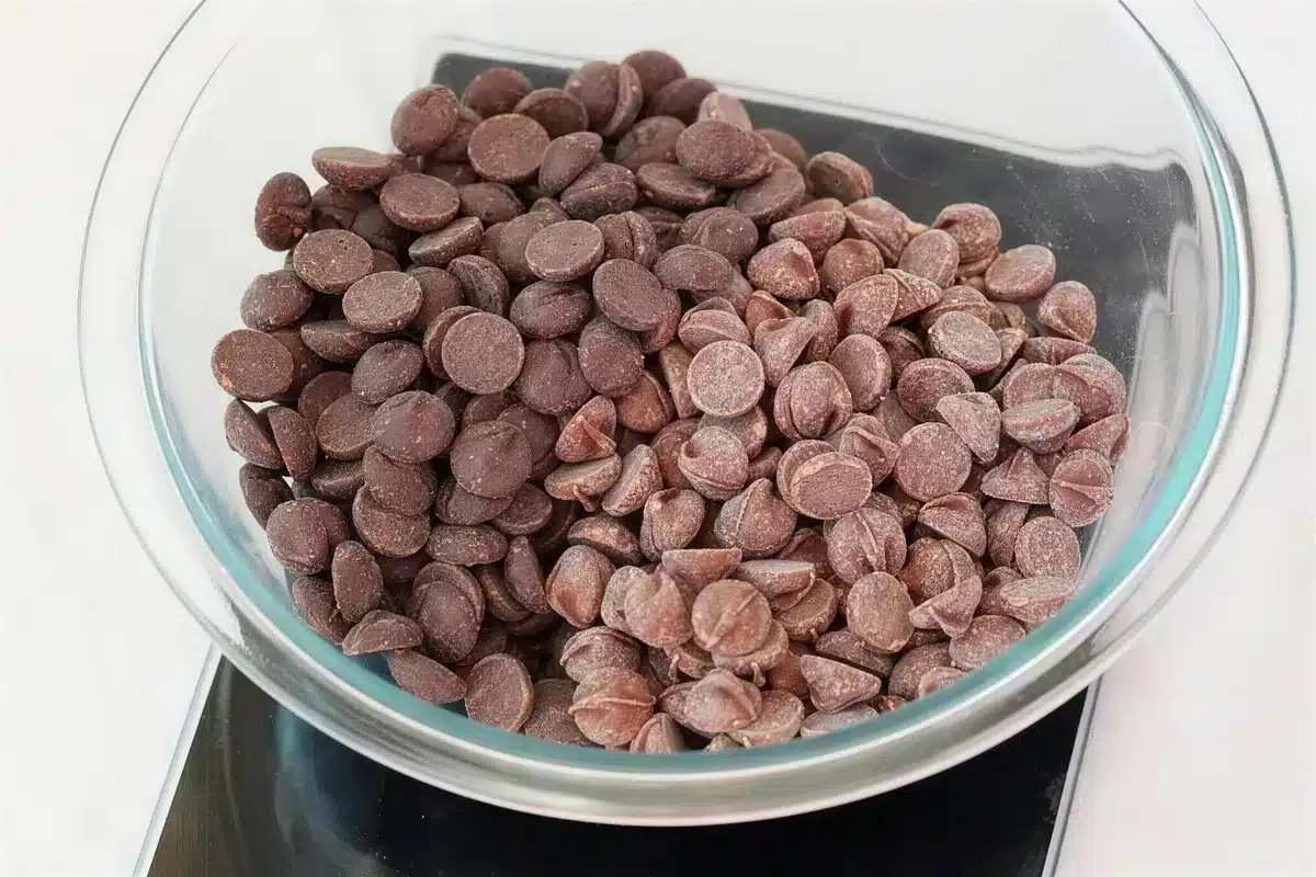 Chocolate wafers heaped in a glass bowl on a kitchen scale