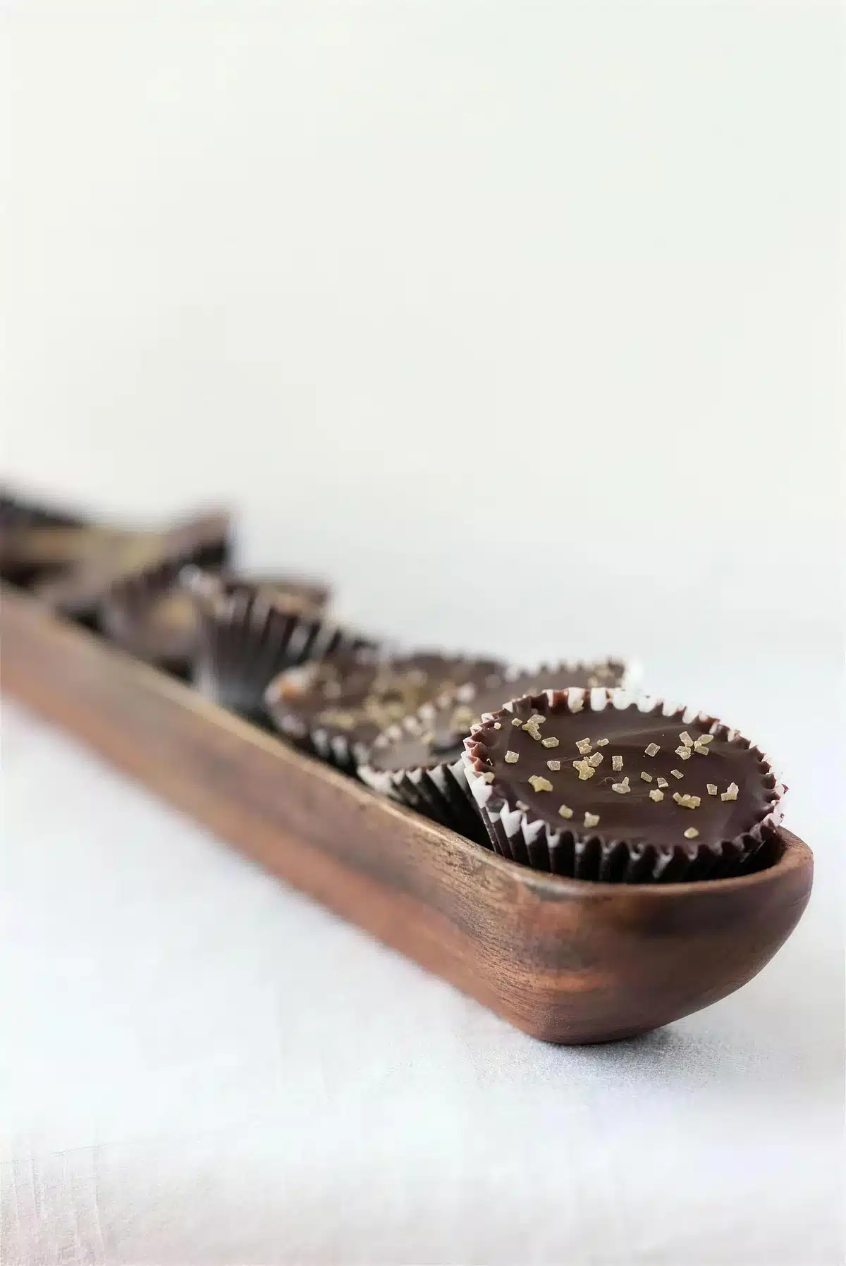 Homemade peanut butter cups finished with gold sprinkles on a wooden tray