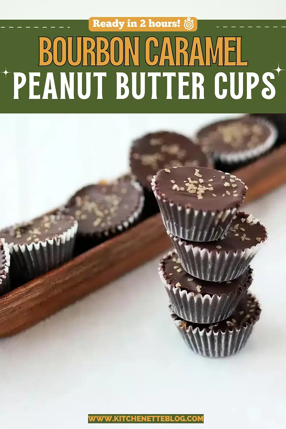 Dark chocolate candies stacked on a narrow wooden tray, one cut open to show the pale filling