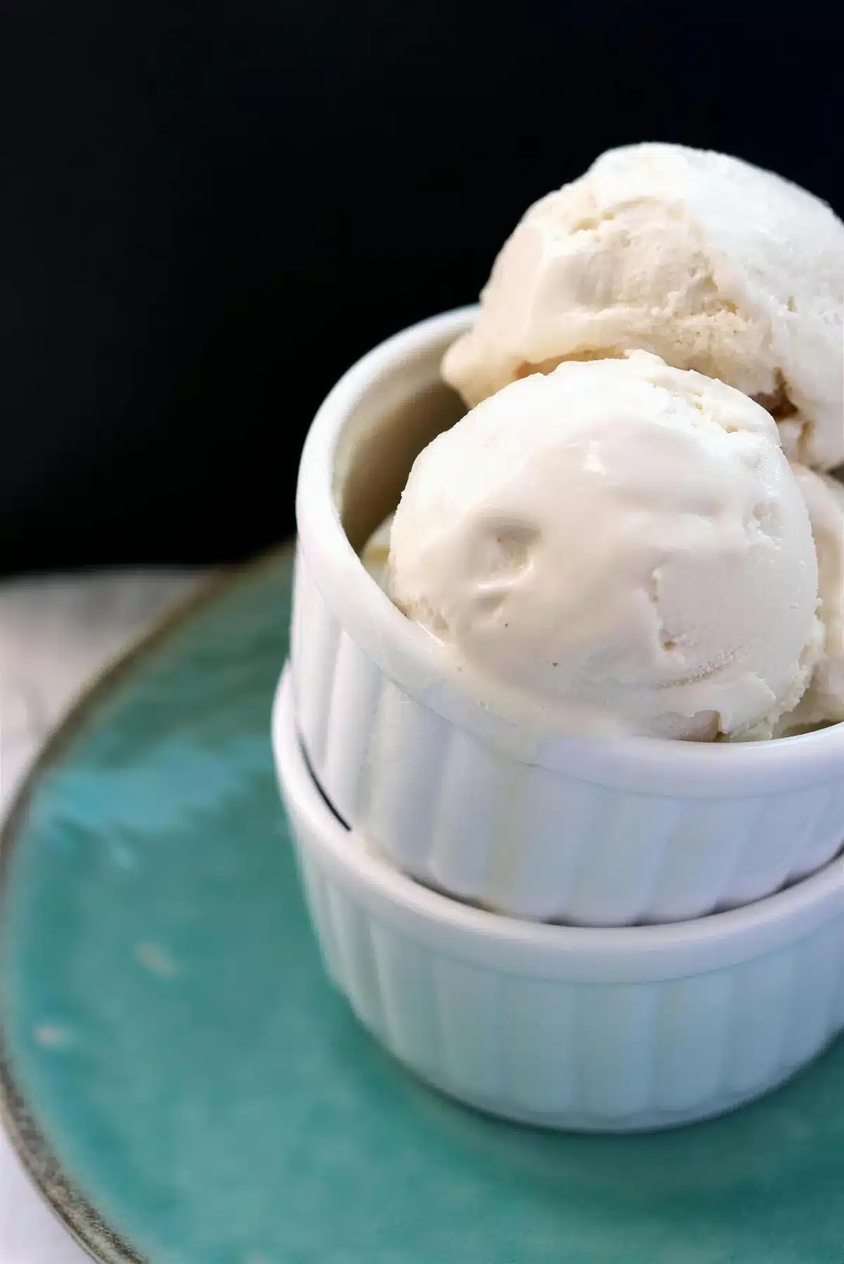 Homemade frozen yogurt in two stacked ramekins on a teal ceramic plate