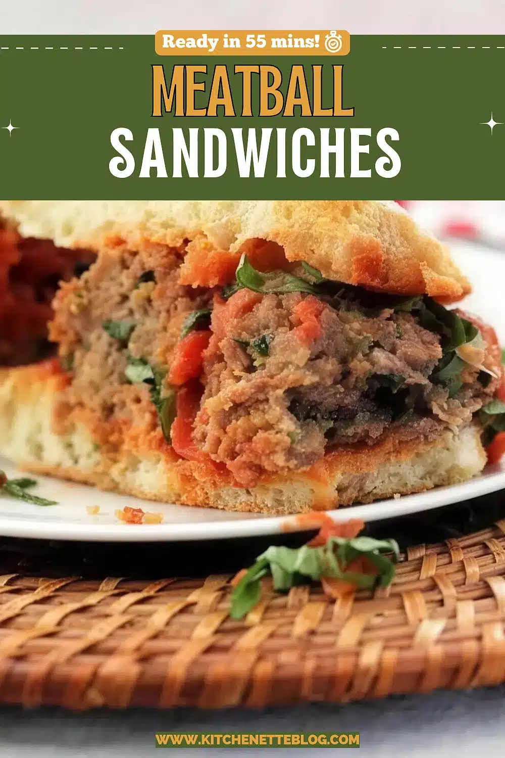 A split ciabatta roll packed with saucy meatballs, roasted peppers and basil, on a white plate over a rattan mat