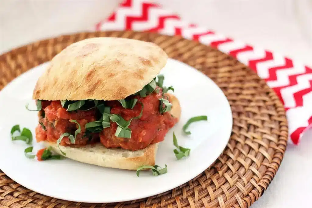 Toasted ciabatta roll piled with saucy spheres and shredded basil