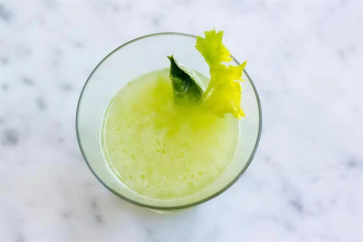 Basil gimlet seen from above in a footed glass with a celery frond