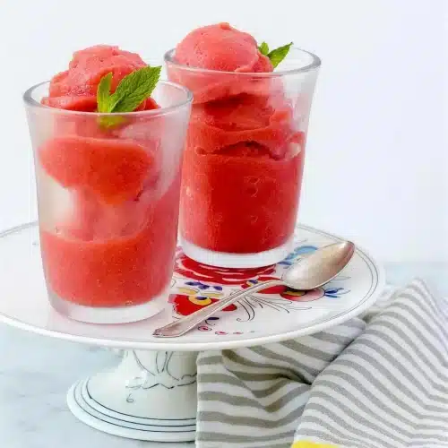 Strawberry sorbet in two glasses with mint leaves on a floral plate